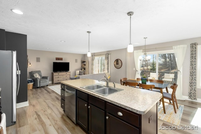 kitchen with light countertops, light wood-style floors, stainless steel appliances, and a sink