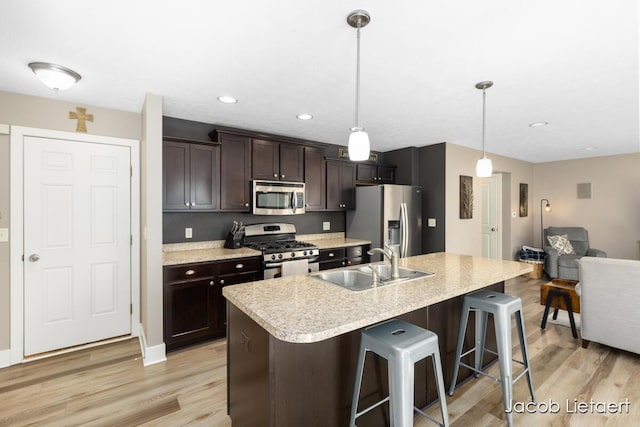 kitchen featuring dark brown cabinets, light countertops, light wood-style floors, stainless steel appliances, and a sink