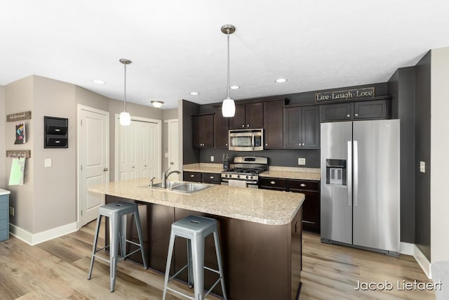 kitchen featuring a sink, light wood-type flooring, appliances with stainless steel finishes, and a breakfast bar