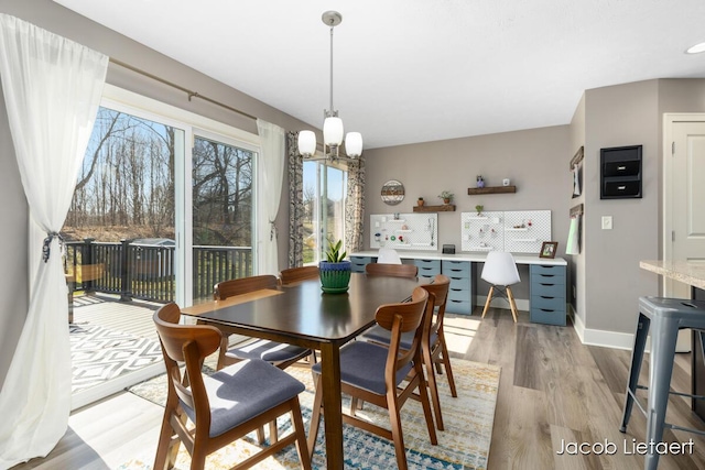 dining area featuring light wood finished floors, a chandelier, and baseboards