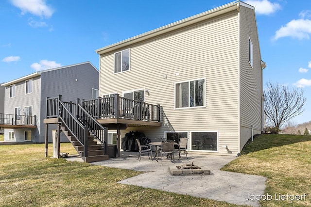 back of property with a lawn, a patio, an outdoor fire pit, stairway, and a wooden deck