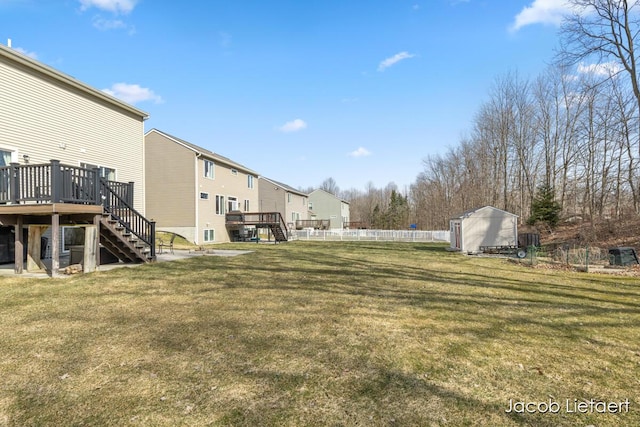 view of yard with a storage unit, fence, an outdoor structure, a wooden deck, and stairs