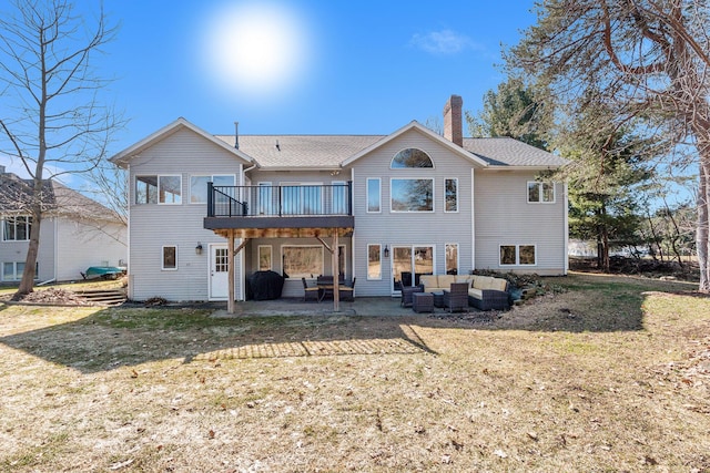 back of property featuring a lawn, outdoor lounge area, a wooden deck, a chimney, and a patio area