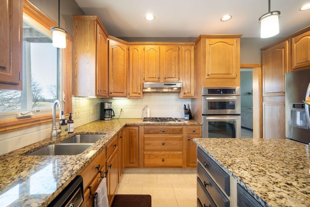 kitchen featuring under cabinet range hood, backsplash, stainless steel appliances, and a sink