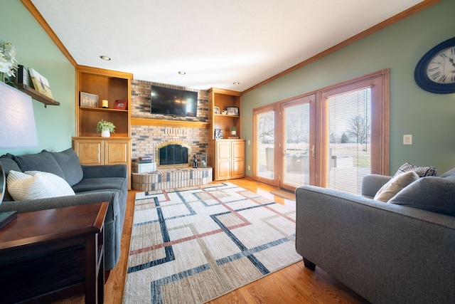 living area featuring a brick fireplace, built in shelves, wood finished floors, and ornamental molding