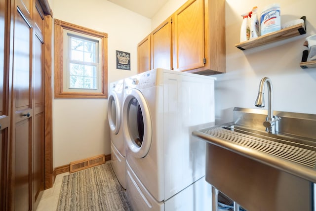 laundry room featuring visible vents, baseboards, washing machine and dryer, cabinet space, and a sink