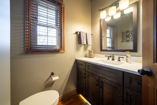 bathroom featuring toilet, plenty of natural light, vanity, and baseboards