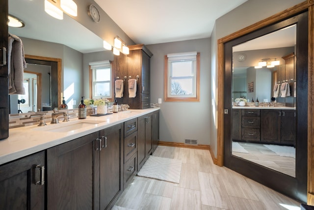 full bath featuring visible vents, a sink, baseboards, and double vanity