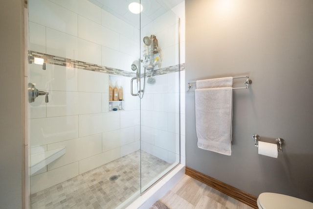 bathroom with baseboards, toilet, and a stall shower