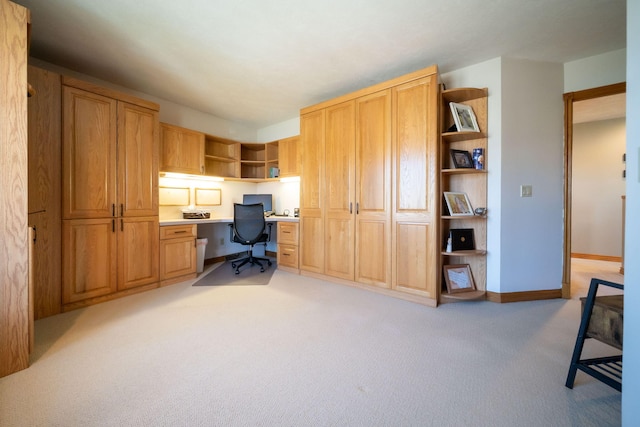 home office with baseboards, light colored carpet, and built in study area