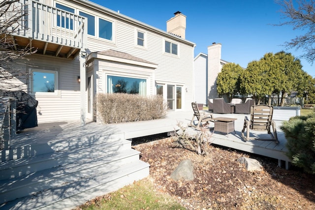 back of property with an outdoor living space, a chimney, and a balcony