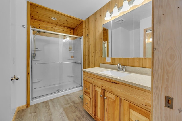 bathroom with vanity, a shower stall, wood finished floors, and visible vents