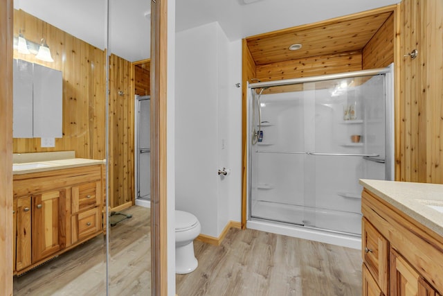 full bath featuring vanity, a shower stall, wooden walls, and wood finished floors