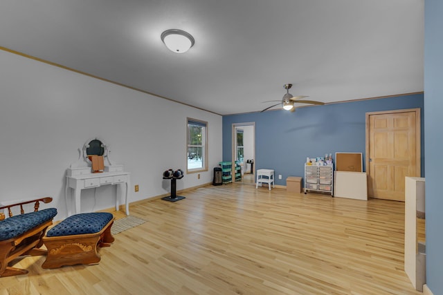 living area with ornamental molding, a ceiling fan, baseboards, and wood finished floors