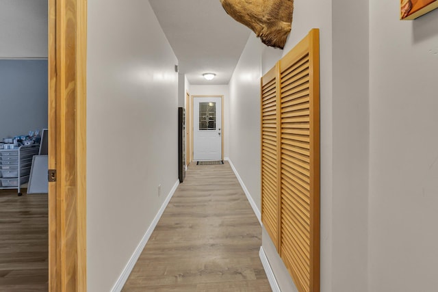 hall featuring light wood-style floors and baseboards