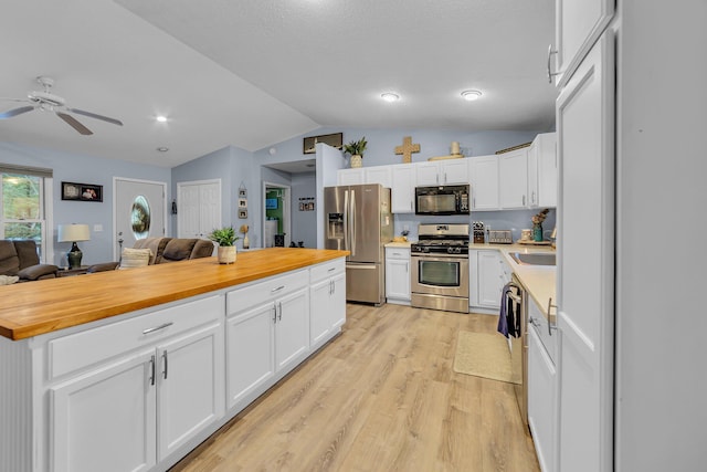 kitchen featuring open floor plan, appliances with stainless steel finishes, white cabinets, light wood finished floors, and wooden counters