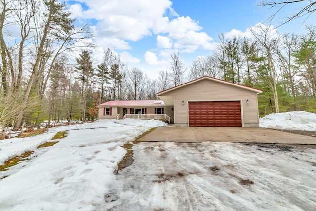 view of front of home featuring covered porch, concrete driveway, a garage, and metal roof