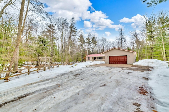 view of snowy exterior featuring a garage and an outdoor structure