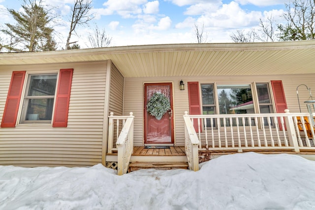 snow covered property entrance featuring covered porch