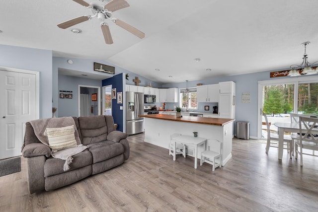 living room with lofted ceiling, light wood-style flooring, a ceiling fan, and baseboards