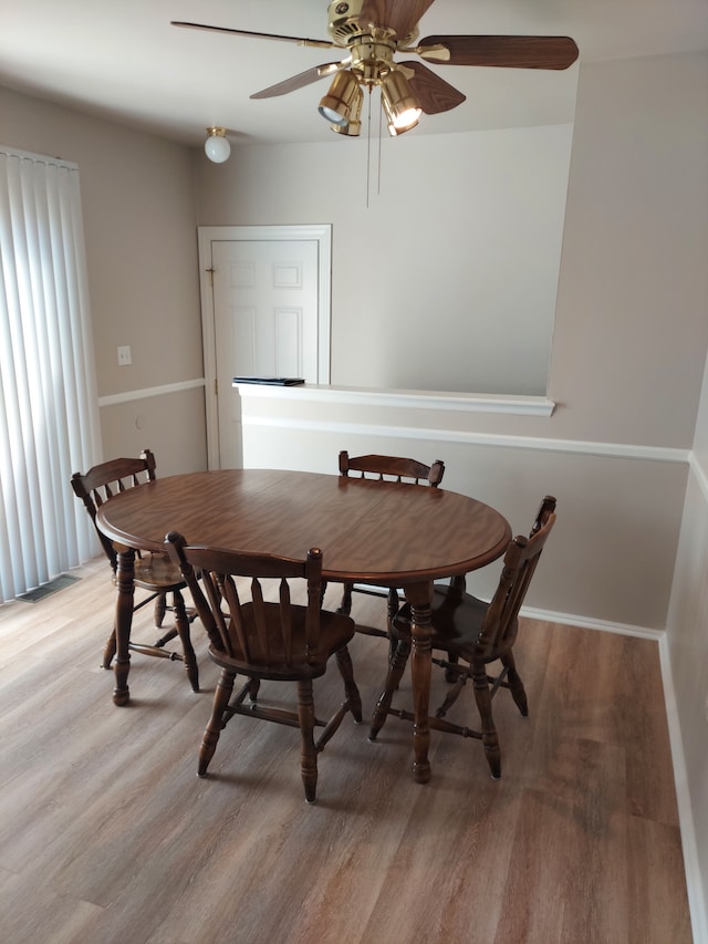 dining space featuring baseboards, visible vents, light wood finished floors, and ceiling fan