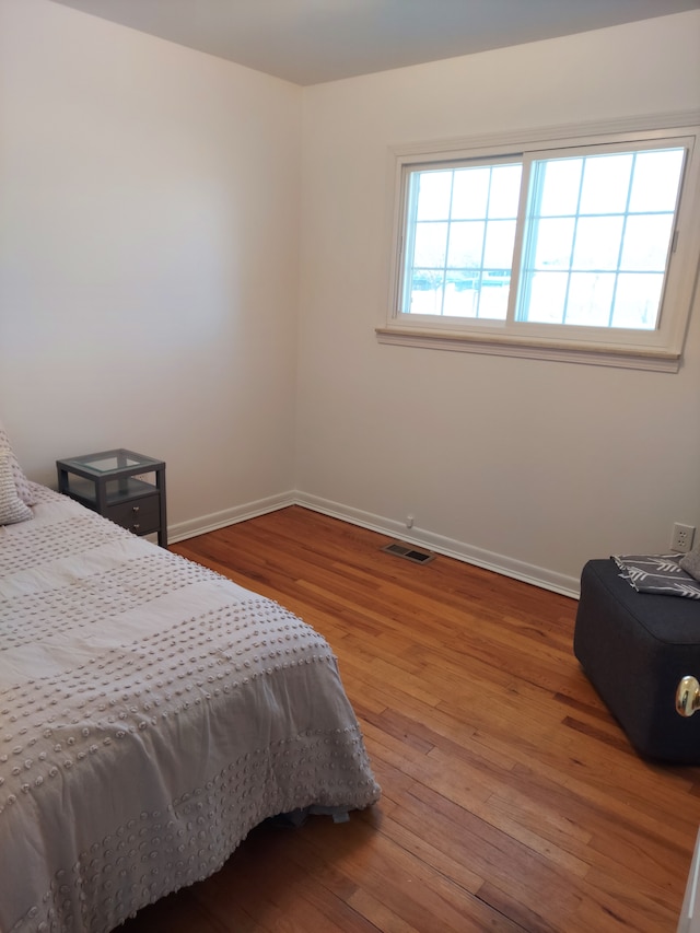 bedroom with visible vents, baseboards, and hardwood / wood-style flooring