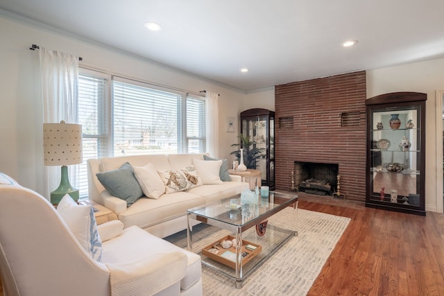 living room featuring recessed lighting, a fireplace, ornamental molding, and wood finished floors