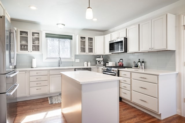 kitchen with decorative backsplash, light wood-style flooring, white cabinets, stainless steel appliances, and a sink