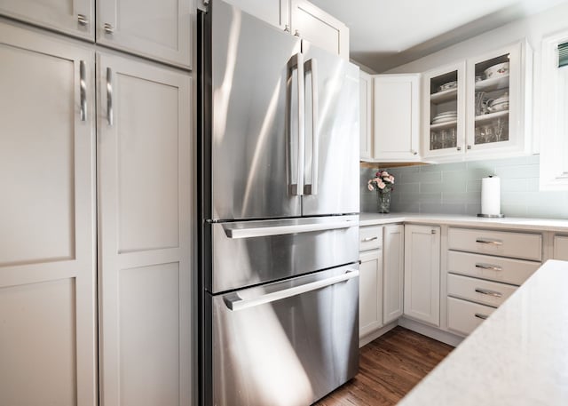 kitchen featuring glass insert cabinets, tasteful backsplash, light countertops, and freestanding refrigerator