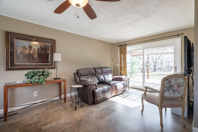 living room with ceiling fan, a textured ceiling, and baseboards