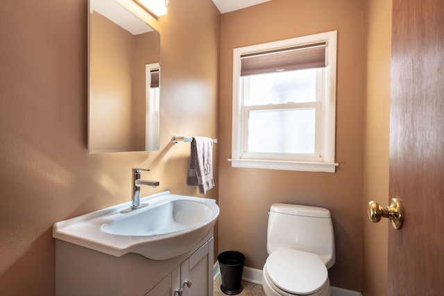 half bath with baseboards, toilet, and vanity