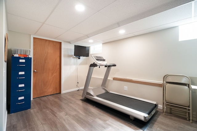 workout room with recessed lighting, wood finished floors, baseboards, and a paneled ceiling