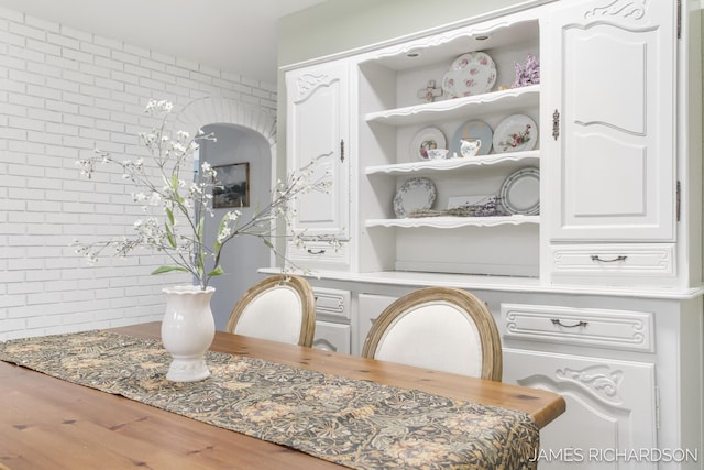 dining space with wood finished floors and brick wall