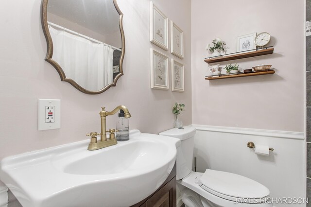 bathroom with curtained shower, toilet, and a sink