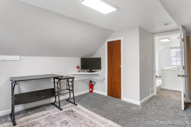 carpeted office space featuring baseboards and lofted ceiling