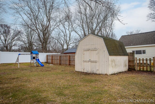 view of shed featuring a playground and a fenced backyard