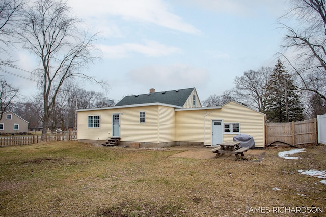 rear view of property with a fenced backyard, a chimney, entry steps, crawl space, and a lawn