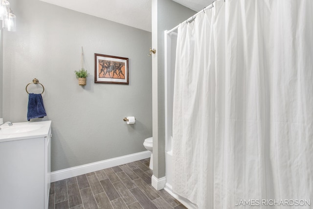 full bath with baseboards, wood tiled floor, toilet, a shower with curtain, and vanity