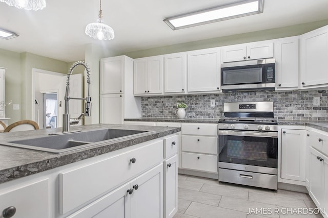 kitchen with backsplash, white cabinets, stainless steel appliances, and a sink