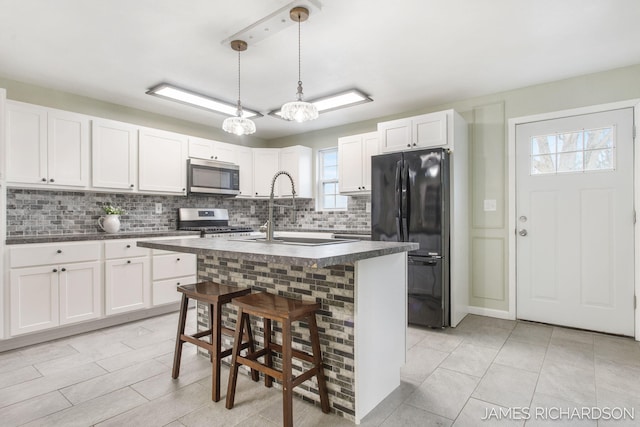 kitchen with dark countertops, tasteful backsplash, appliances with stainless steel finishes, white cabinetry, and a sink