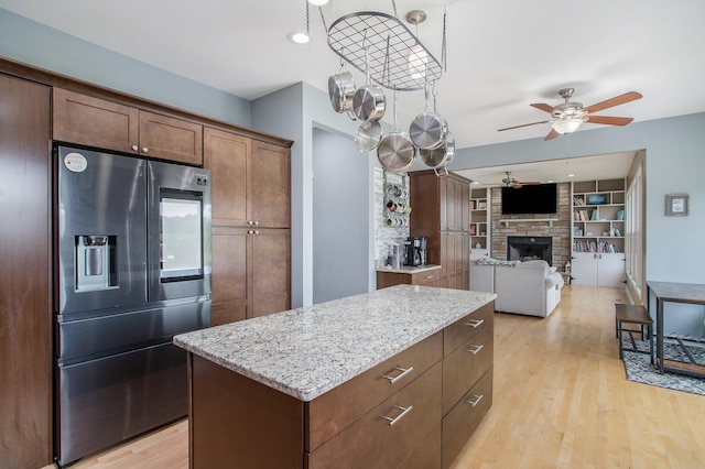 kitchen featuring light wood finished floors, a fireplace, a kitchen island, and stainless steel fridge with ice dispenser