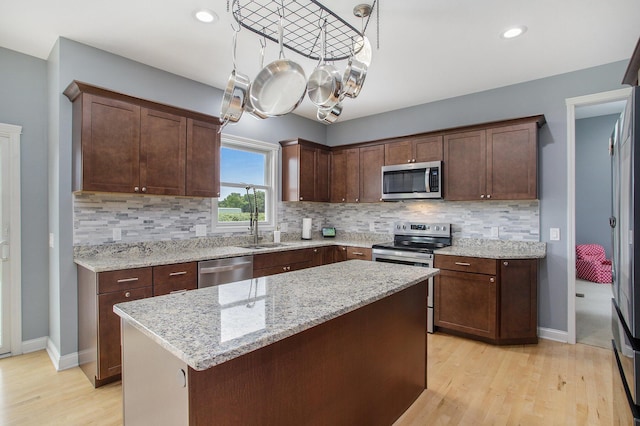 kitchen with backsplash, stainless steel appliances, and light wood-style floors