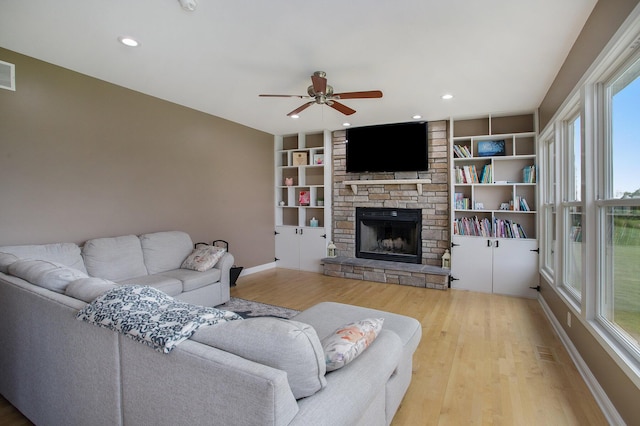 living area featuring wood finished floors, visible vents, baseboards, a fireplace, and ceiling fan