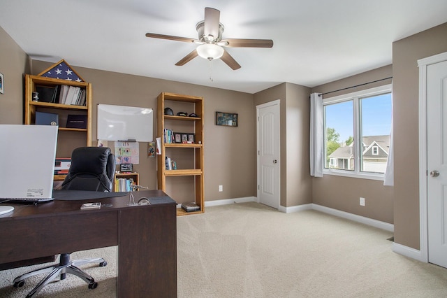 home office with light colored carpet, a ceiling fan, and baseboards