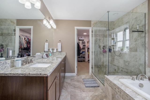 full bath featuring tiled bath, a walk in closet, a stall shower, and vanity