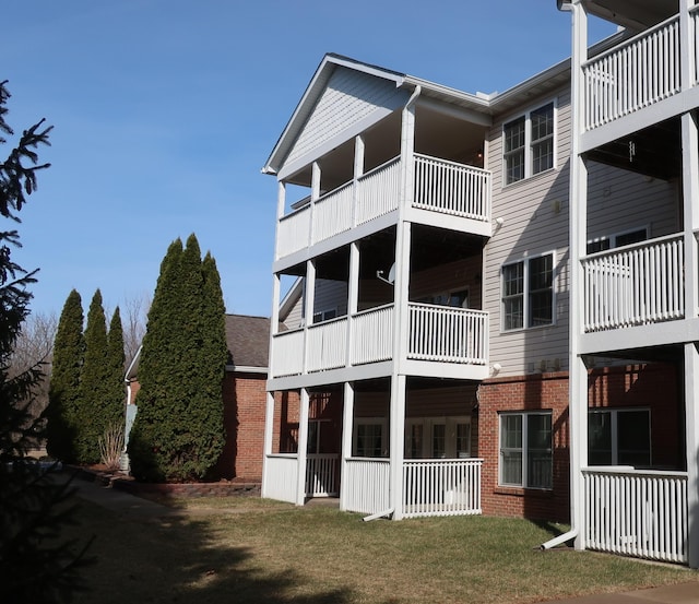 rear view of property featuring brick siding and a yard