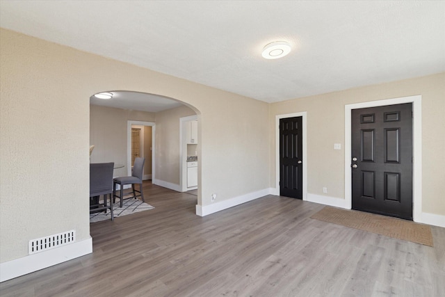 interior space with visible vents, arched walkways, baseboards, and wood finished floors