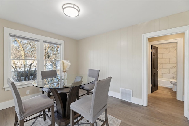 dining area featuring baseboards, visible vents, and light wood finished floors