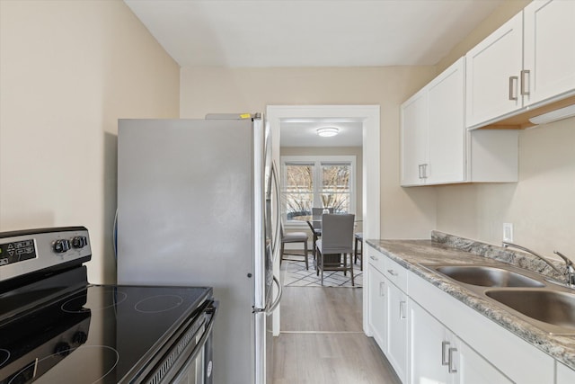 kitchen featuring light wood finished floors, a sink, appliances with stainless steel finishes, white cabinets, and light countertops