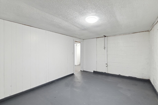 finished basement featuring a textured ceiling and concrete block wall